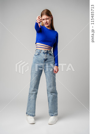 Young Woman Pointing Finger Down at Camera in studio 115485713
