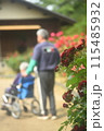 花の咲く公園を散歩する車いすの老人と介助する介護士 115485932