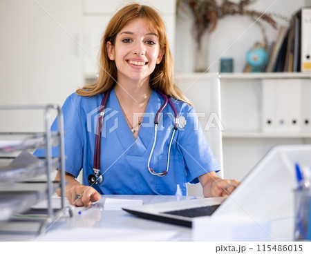 Woman doctor sitting at workplace with computer in her office 115486015
