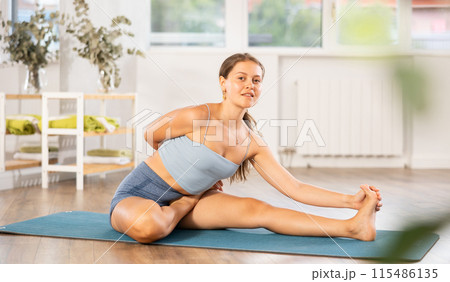 Lover of active lifestyle on yoga mat perform doing Parivritta Janu Shirshasana in gym 115486135