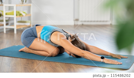 Young woman doing restful pose Balasana in yoga studio 115486202