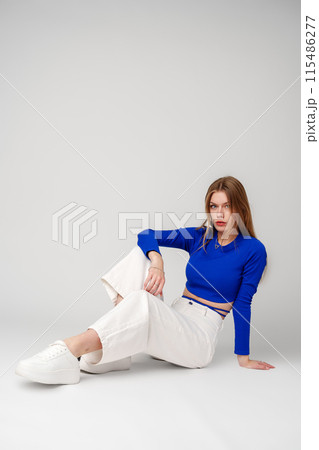 Young Woman model in Blue Top and White Pants posing on white background 115486277