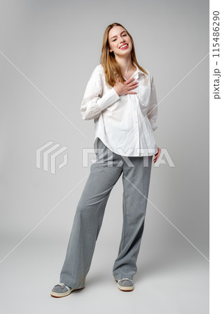 Joyful Young Blonde Woman Smiling against gray background Joyful Young Blonde Woman Smiling against gray background 115486290
