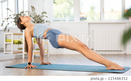 Lover of active lifestyle on yoga mat perform doing Ardha chakrasana in gym 115486352