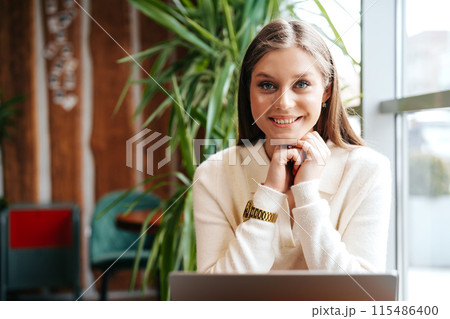 Smiling Woman Working on Laptop at a Cafe During Daytime 115486400