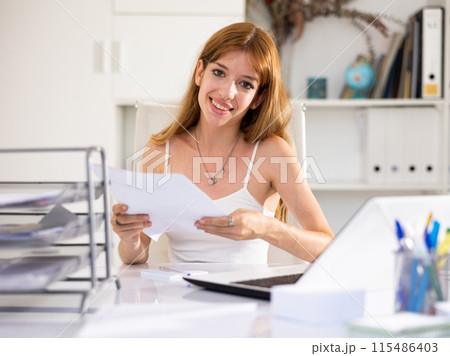 Portrait of smiling woman office worker doing paperwork 115486403