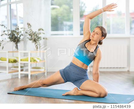 Athletic young woman enjoying daily yoga practice in studio 115486439