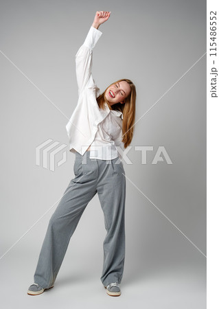 Jubilant Young Woman Celebrating a Victory With a Raised Fist in Studio Jubilant Young Woman Celebrating a Victory With a Raised Fist in Studio 115486552