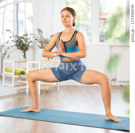 Young girl performing Utkata Konasana with hands in namaste 115486646