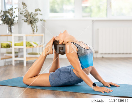 Sportive girl practicing cobra pose of yoga in light room 115486655