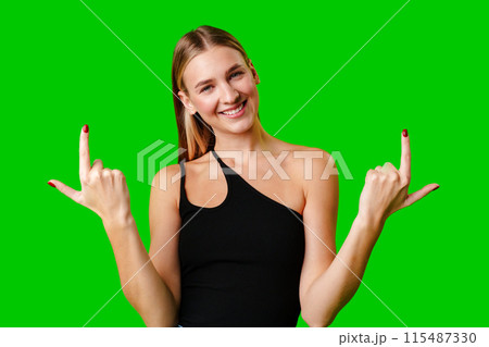 Young Woman Pointing Up Against Green Background Young Woman Pointing Up Against Green Background 115487330