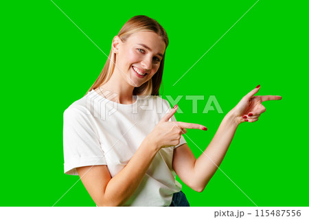 Young Woman Pointing at Something against green background Young Woman Pointing at Something against green background 115487556