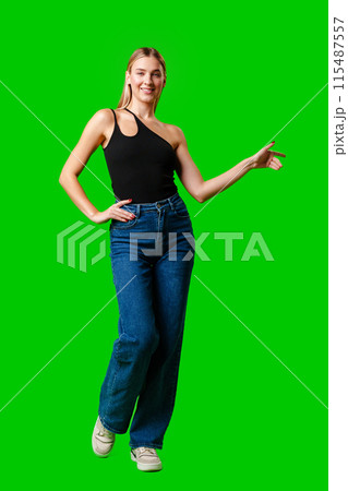 Young Woman Pointing at Something against green background 115487557