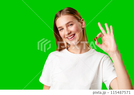 Young Woman Giving Thumbs Up Sign on Green Screen Young Woman Giving Thumbs Up Sign on Green Screen 115487571