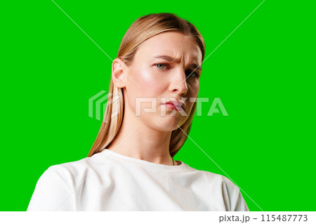 Young Woman With Pursed Lips Expressing Skepticism Against Green Screen Background 115487773