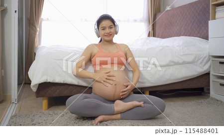 A portrait of happy Asian pregnant woman in bedroom at home. Having a baby. Training workout. Exercise indoor with sport equipment. Athletic. Family people lifestyle. Mom love. Recreation. 115488401