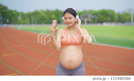 A portrait of happy Asian pregnant woman running on rubber floor, track on a sports stadium. Sport and recreation background. Having a baby. Family people lifestyle. Mom lifestyle. 115488566