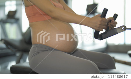 A portrait of happy Asian pregnant woman at gym fitness center club. Having a baby. Training workout. Exercise indoor with sport equipment. Athletic. Family people lifestyle. Mom love. Recreation. A portrait of happy Asian pregnant woman at gym fitness center club. Having a baby. Training workout. Exercise indoor with sport equipment. Athletic. Family people lifestyle. Mom love. Recreation. 115488617