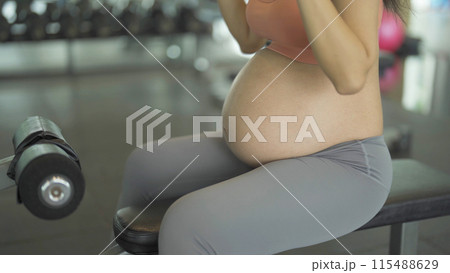 A portrait of happy Asian pregnant woman at gym fitness center club. Having a baby. Training workout. Exercise indoor with sport equipment. Athletic. Family people lifestyle. Mom love. Recreation. 115488629