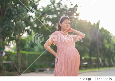 A portrait of happy Asian pregnant woman walking in public garden park on vacation. Love of mother. Having a baby. Family people lifestyle. A portrait of happy Asian pregnant woman walking in public garden park on vacation. Love of mother. Having a baby. Family people lifestyle. 115488819