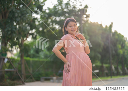 A portrait of happy Asian pregnant woman walking in public garden park on vacation. Love of mother. Having a baby. Family people lifestyle. A portrait of happy Asian pregnant woman walking in public garden park on vacation. Love of mother. Having a baby. Family people lifestyle. 115488825