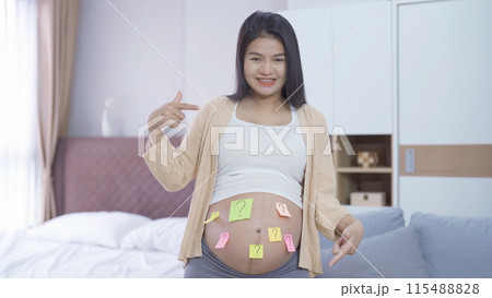 A portrait of happy Asian pregnant woman with blank sex sticky note. Having a baby. Family people lifestyle. Mom love. A portrait of happy Asian pregnant woman with blank sex sticky note. Having a baby. Family people lifestyle. Mom love. 115488828
