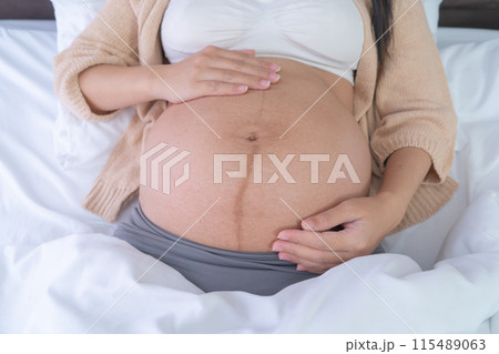 Close up of a Portrait of happy pregnant woman in bedroom at home. Having a baby. Family people lifestyle. Mom love. Close up of a Portrait of happy pregnant woman in bedroom at home. Having a baby. Family people lifestyle. Mom love. 115489063
