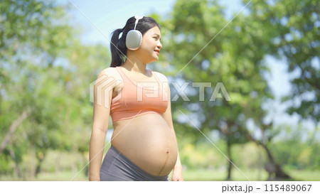 A portrait of happy Asian pregnant woman in yoga class club doing exercise at public garden park. Outdoor sport and recreation. activity with nature trees view. Having a baby. Family people lifestyle. A portrait of happy Asian pregnant woman in yoga class club doing exercise at public garden park. Outdoor sport and recreation. activity with nature trees view. Having a baby. Family people lifestyle. 115489067