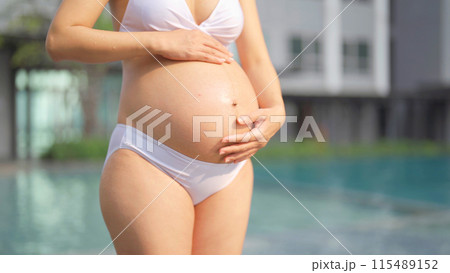 A portrait of happy Asian pregnant woman by the swimming pool. People lifestyle in travel holiday vacation concept. Relaxation. Having a baby. Family people lifestyle. Mom love. 115489152