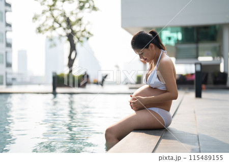 A portrait of happy Asian pregnant woman by the swimming pool. People lifestyle in travel holiday vacation concept. Relaxation. Having a baby. Family people lifestyle. Mom love. 115489155