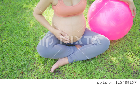 A portrait of happy Asian pregnant woman in yoga class club doing exercise at public garden park. Outdoor sport and recreation. activity with nature trees view. Having a baby. Family people lifestyle. 115489157