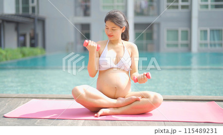 A portrait of happy Asian pregnant woman by the swimming pool. People lifestyle in travel holiday vacation concept. Relaxation. Having a baby. Family people lifestyle. Mom love. 115489231