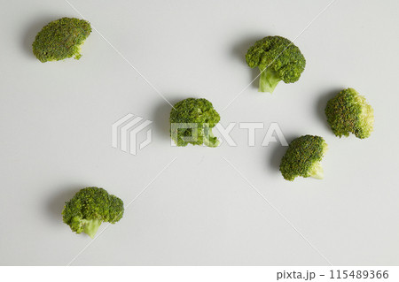 Minimalist photo with the main composition as green broccoli, which isolated and scattered on white flat. Top view photo with blank space for advertise products made from broccoli 115489366