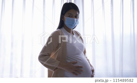 Depressed lonely Asian pregnant divorce woman with a mask for protecting covid-19 in bedroom at home. Having a baby. Family people lifestyle. Mom. quarantine 115489582