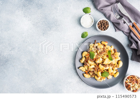 Stewed pasta with minced beef and vegetables, macaroni in Navy style on a plate. grey concrete background. Copy space. Stewed pasta with minced beef and vegetables, macaroni in Navy style on a plate. grey concrete background. Copy space. 115490573
