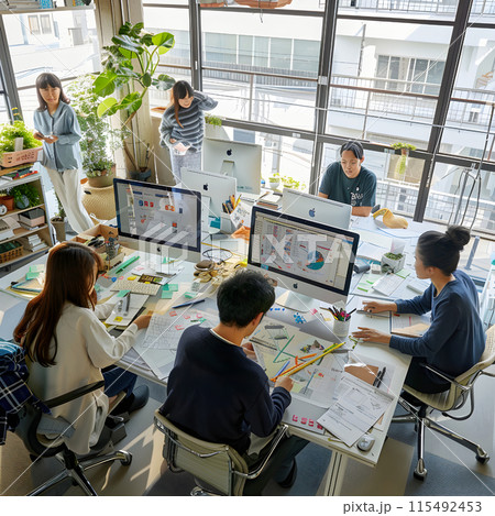 オフィス、オープンスペース、チーム作業、パソコン使用、窓からの自然光、観葉植物、プロジェクト計画 115492453