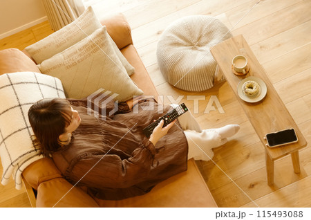 ソファーに座ってテレビを見てくつろいでいる女性 115493088