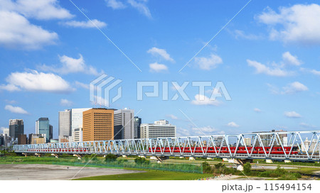 川崎の都市風景　六郷橋ですれ違う京急線の電車と川崎駅前のビル群【神奈川県・川崎市】 115494154