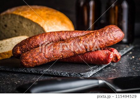 Smoked salami sausages on cutting board on black table. 115494529