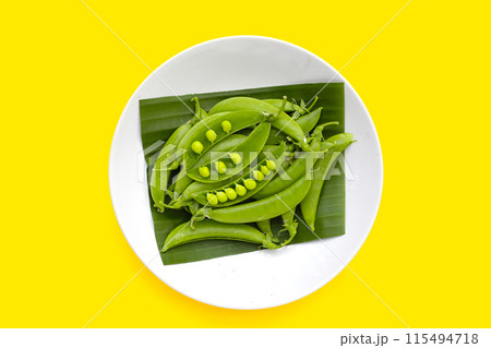 Fresh young green peas on yellow background. Fresh young green peas on yellow background. 115494718