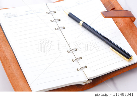 リング式のシステム手帳を開いてデスクワークをしているイメージ 115495341