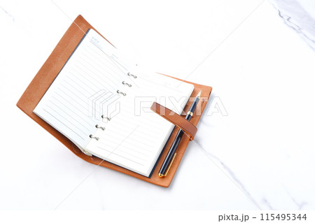 リング式のシステム手帳を開いてデスクワークをしているイメージ 115495344
