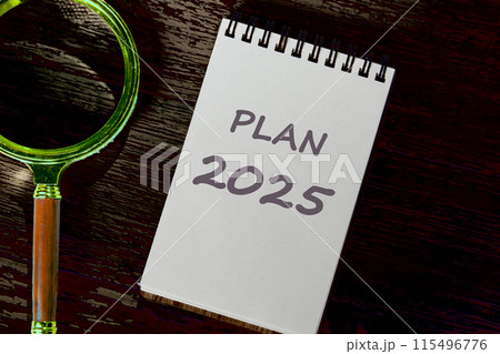 Planning goals and success concept. Text PLAN 2025 on a white notebook in a dark place next to a magnifying glass 115496776