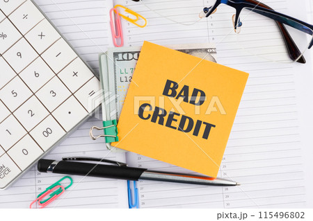Business concept. Bad Credit written on a yellow sticker with money on a business notebook 115496802
