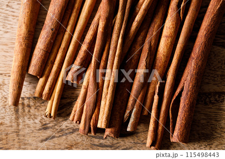 Cinnamon sticks dried tree bark spice on rustic wooden table background. Selective focus. Cinnamon sticks dried tree bark spice on rustic wooden table background. Selective focus. 115498443