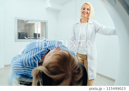 A woman in a white coat stands next to a woman in a blue shirt in a room with a medical machine A woman in a white coat stands next to a woman in a blue shirt in a room with a medical machine 115499023