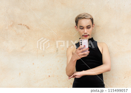 Asian queer LGBT community supporter man with mustache wearing lipstick and jumpsuit using phone Asian queer LGBT community supporter man with mustache wearing lipstick and jumpsuit using phone 115499057