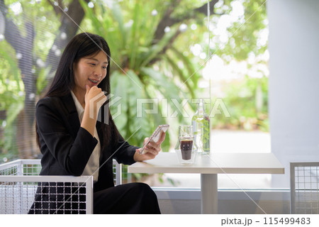 Professional businesswoman using her smartphone in a bright, modern cafe with coffee and greenery Professional businesswoman using her smartphone in a bright, modern cafe with coffee and greenery 115499483