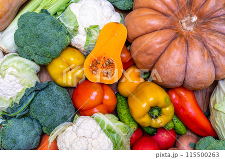 Various vegetables are laid out on a wooden table. Large assortment of vegetables food. pumpkin cabbage broccoli pepper tomatoes carrots and others 115500263