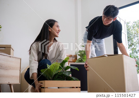Young Couple Moving into New House, Unpacking Boxes and Plants, Starting a New Chapter Together in Their Modern Home, Bright and Cheerful Atmosphere, Fresh Start, Excitement and Anticipation 115501427